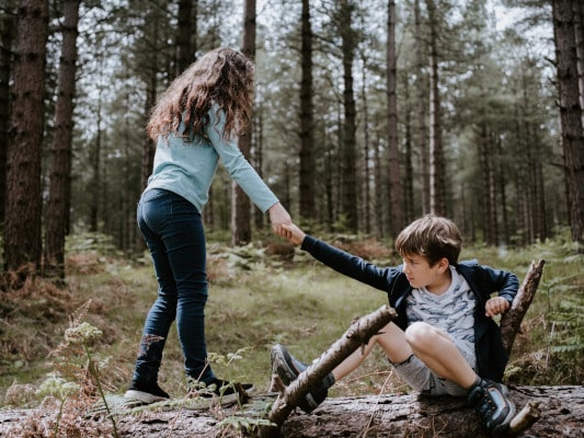 Girl helping boy stand up from the ground