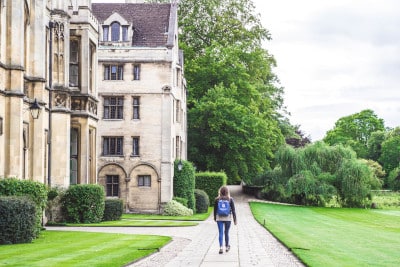 student walking down path with university buildings to the side